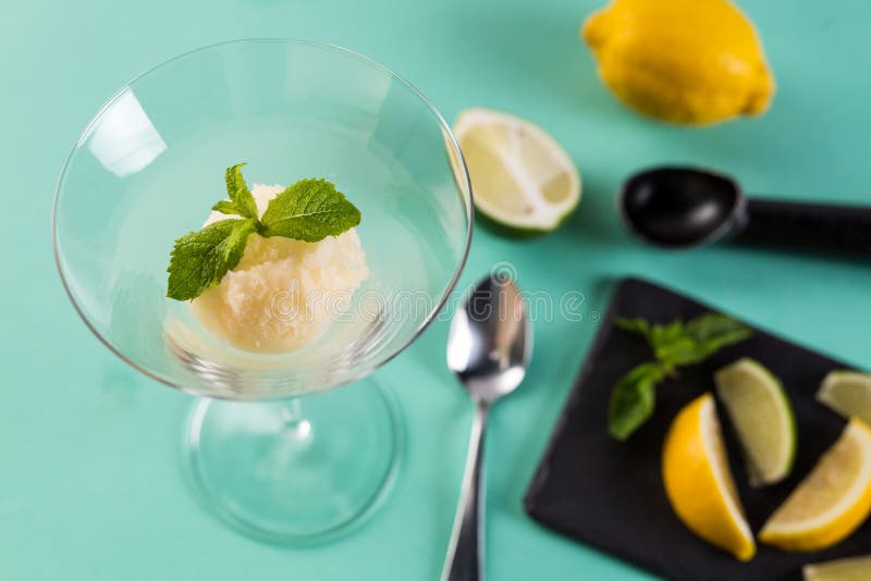 Lemon sorbet garnished with mint leaf. Tasty sorbet in high glass with spoon.