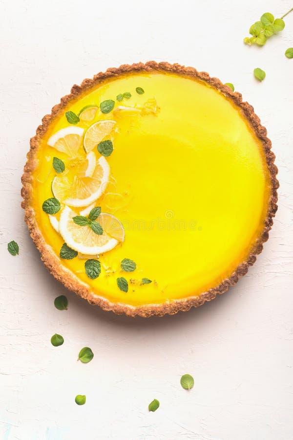 Lemon tart topped with citrus slices and zest on white table background, top view. Copy space. Traditional french cuisine royalty free stock photography