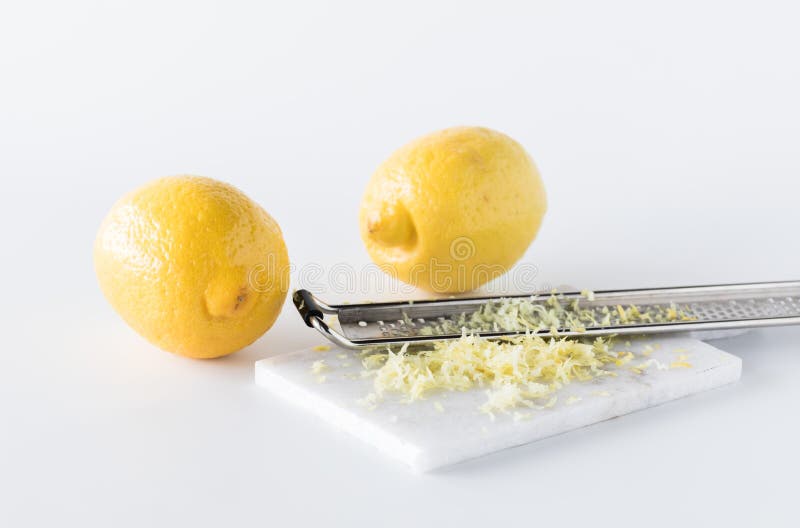 Lemon zest with a microplane and two lemons in behind. A close up of lemon zest with a microplane and two lemons in behind royalty free stock photos