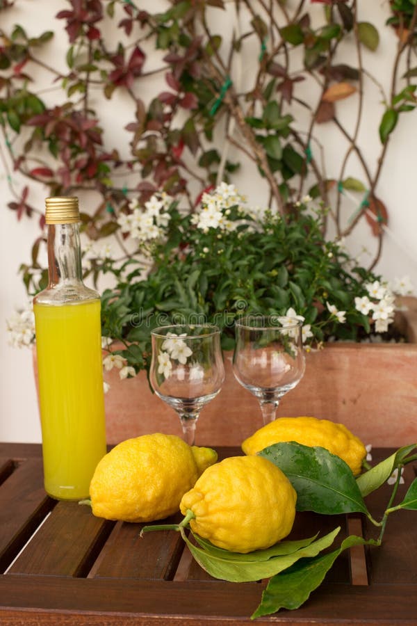 Lemonad eller limoncello i en glasflaska, exponeringsglas, citroner med sidor på en trätabell, i bakgrunden av krukor med dows fotografering för bildbyråer Lemonad eller limoncello i en glasflaska, exponeringsglas, citroner med sidor på en trätabell, i bakgrunden av krukor med dows fotografering för bildbyråer