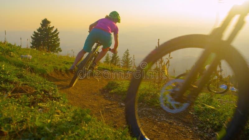 LENS FLARE Four mountain bikers ride into a sharp turn on a sunny spring evening stock photo