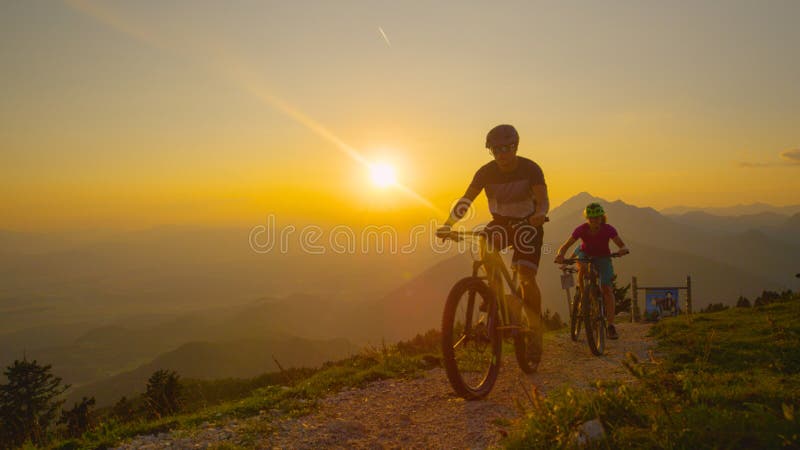 LENS FLARE: Happy travelers enjoying a bicycle ride in the sunlit mountains. stock photo