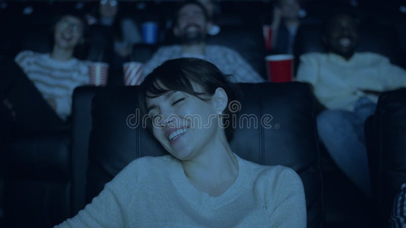 Lent mouvement d'une belle dame qui rit en regardant un film amusant dans un cinéma sombre clips vidéos