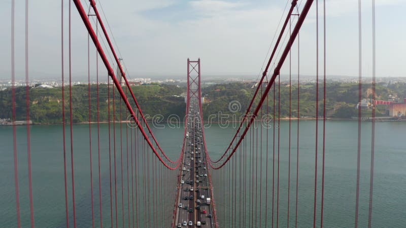 Lenta muñeca aérea en vista del denso tráfico de vehículos de múltiples carriles a través del puente rojo ponte 25 de abril en lis almacen de video