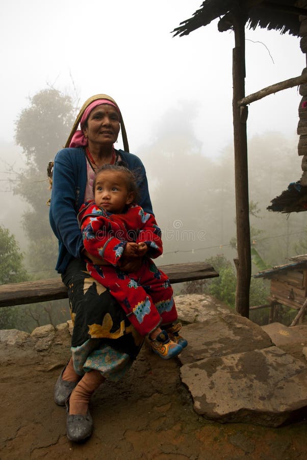 A Lepcha woman is sitting with her child on her lap in front of her home at Lava near Darjeeling. Lepchas are the ancient tribe of these locality. A Lepcha woman is sitting with her child on her lap in front of her home at Lava near Darjeeling. Lepchas are the ancient tribe of these locality.