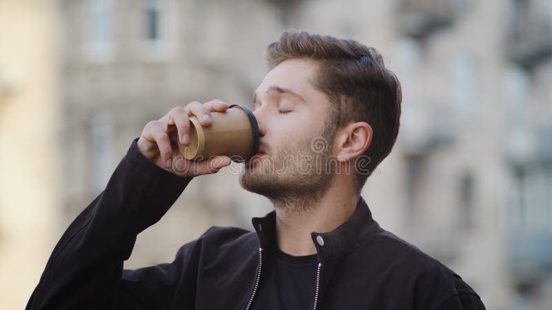Ler kille som dricker kaffe utanför. snygg man som njuter av kaffe utomhus arkivfilmer