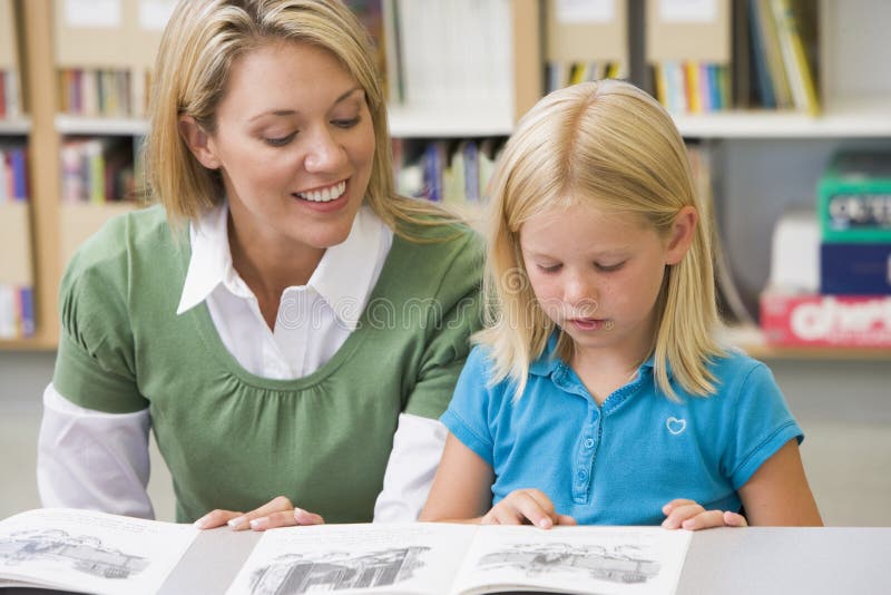Leraar die student met lezingsvaardigheden helpt stock afbeeldingen Leraar die student met lezingsvaardigheden helpt stock afbeeldingen