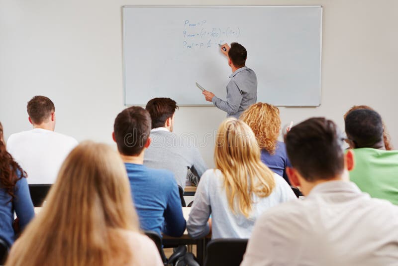 Teacher on whiteboard in class teaching business studies in university. Teacher on whiteboard in class teaching business studies in university