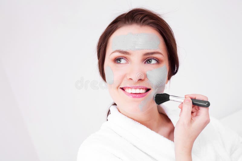 Young woman applying a deep cleansing clay mask with a brush. Young woman applying a deep cleansing clay mask with a brush
