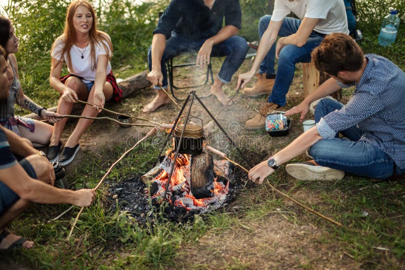 Les adolescents apprennent à cuisiner des saucisses en feu photo libre de droits