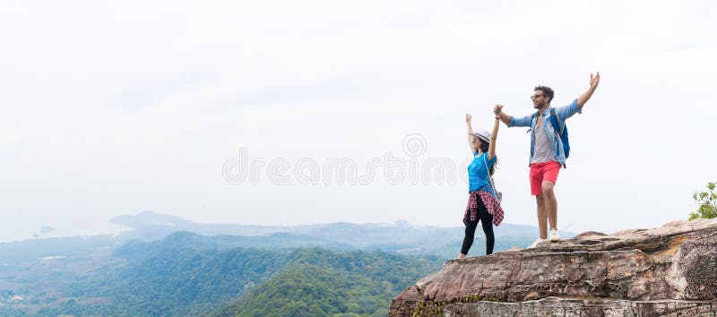 Les ajouter de touristes au sac à dos jugeant des mains augmentées sur le dessus de montagne apprécient le beau panorama de paysa photographie stock libre de droits Les ajouter de touristes au sac à dos jugeant des mains augmentées sur le dessus de montagne apprécient le beau panorama de paysa photographie stock libre de droits
