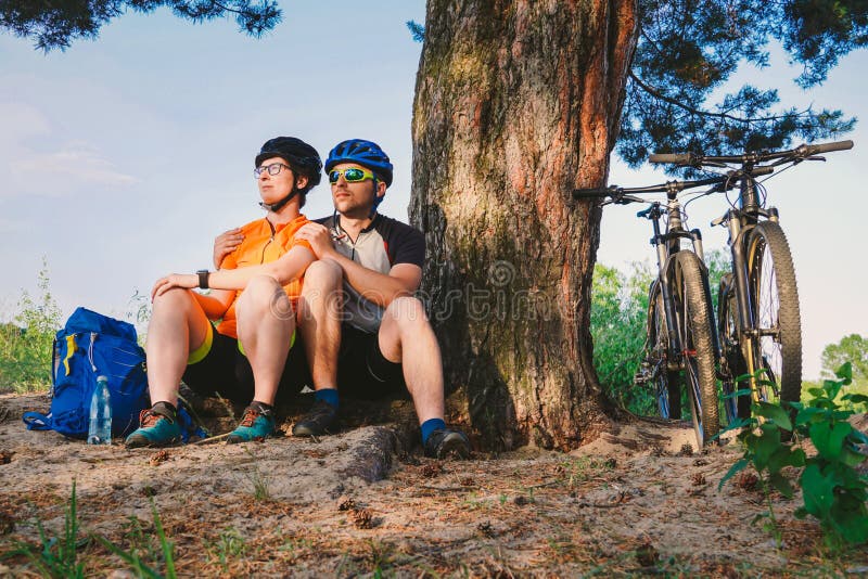 Les ajouter heureux au vélo de montagne se reposent embrassant la nature de loisirs dehors les couples heureux, mènent un mode de image libre de droits Les ajouter heureux au vélo de montagne se reposent embrassant la nature de loisirs dehors les couples heureux, mènent un mode de image libre de droits