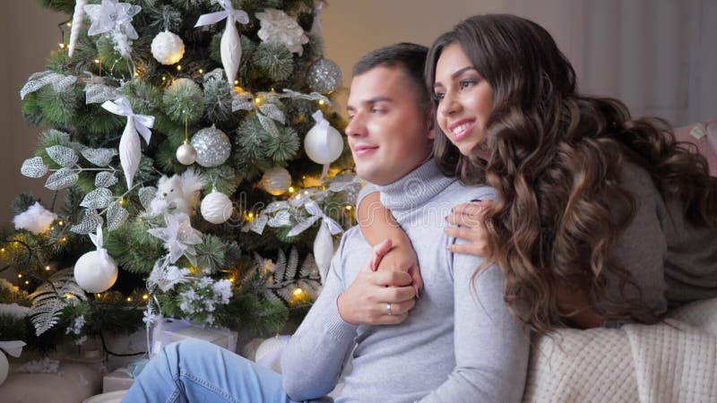Les amants caressent sur l'arbre de sapin de fond la veille de Noël à la maison, des moments doux