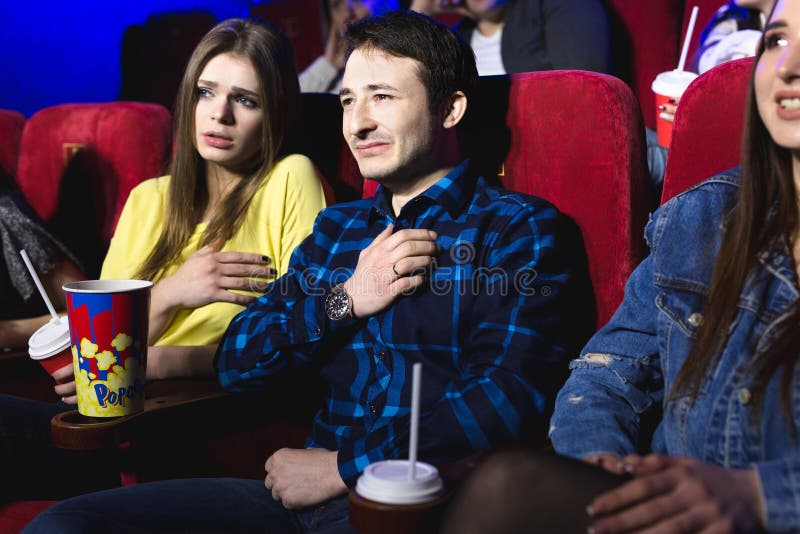 Friends a man and a woman are watching a movie in a movie theater crying. Friends a man and a woman are watching a movie in a movie theater crying.