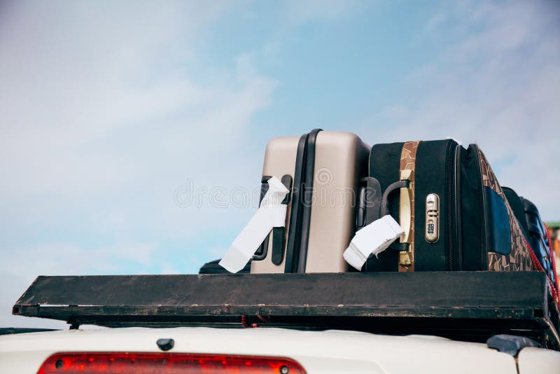 Les bagages et les sacs ont arrangé sur le toit de voiture prêt pour un voyage à l'arrière-plan de ciel photo stock Les bagages et les sacs ont arrangé sur le toit de voiture prêt pour un voyage à l'arrière-plan de ciel photo stock