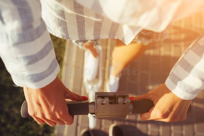 Les belles mains femelles tiennent le scooter par les poignées photo stock Les belles mains femelles tiennent le scooter par les poignées photo stock