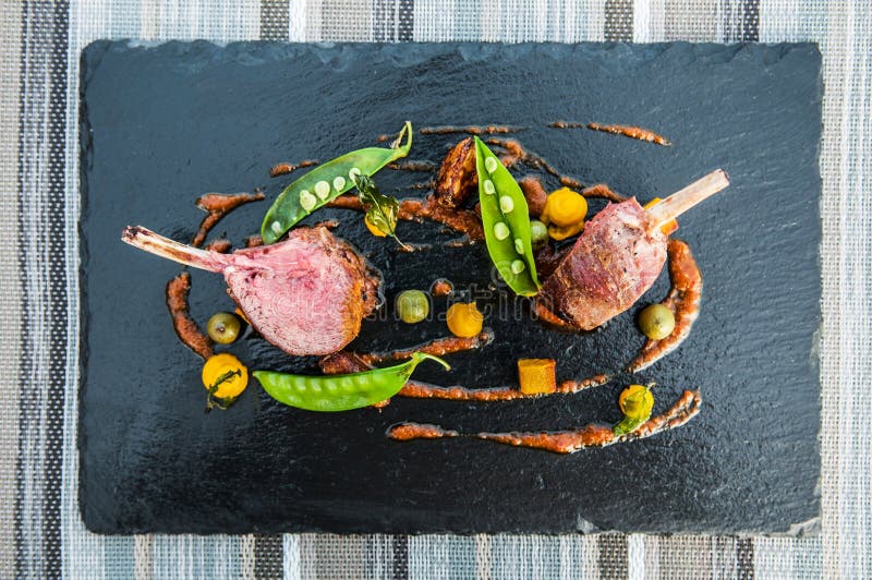 Les belles nervures rôties d'agneau avec le haricot vert et l'herbe Sauce sur le bl photographie stock libre de droits Les belles nervures rôties d'agneau avec le haricot vert et l'herbe Sauce sur le bl photographie stock libre de droits