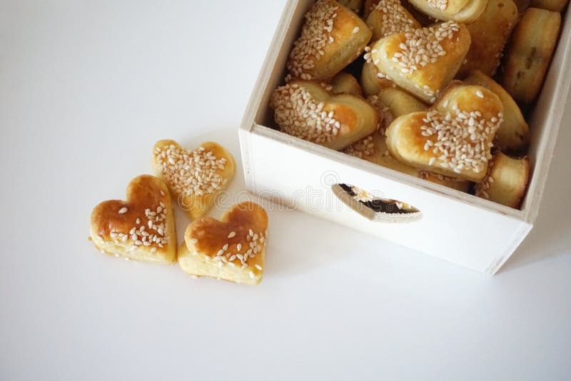 Les biscuits de sésame dans la forme du coeur, appartement s'étendent sur le fond blanc image stock Les biscuits de sésame dans la forme du coeur, appartement s'étendent sur le fond blanc image stock