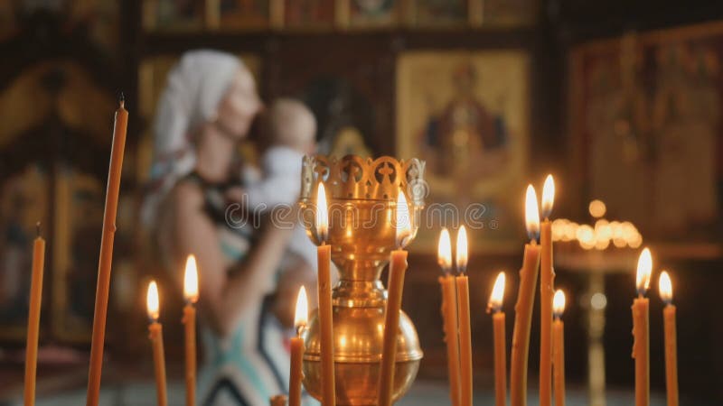 Les bougies est sur le premier plan, mère avec le bébé sur le fond brouillé dans l'église