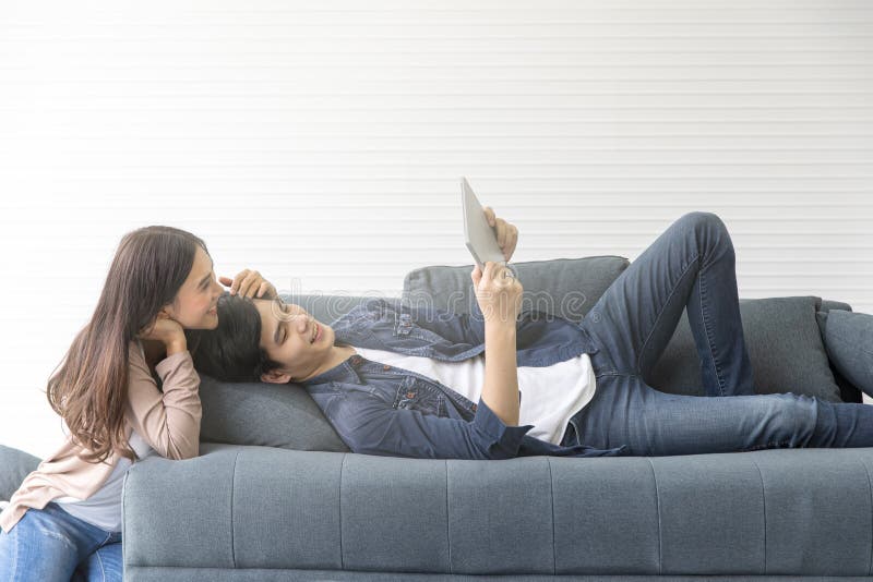 Les couples asiatiques semblent bons sur le sofa Regardez quelque chose par le Th photos stock Les couples asiatiques semblent bons sur le sofa Regardez quelque chose par le Th photos stock