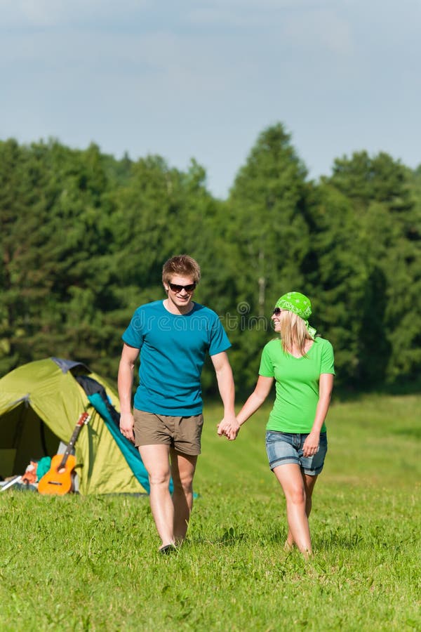 Les couples campants de jeunes retiennent la campagne d'été de mains image libre de droits Les couples campants de jeunes retiennent la campagne d'été de mains image libre de droits