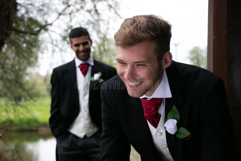 Les couples gais des mariés posent pour des photographies par un lac leur jour du mariage photos stock Les couples gais des mariés posent pour des photographies par un lac leur jour du mariage photos stock