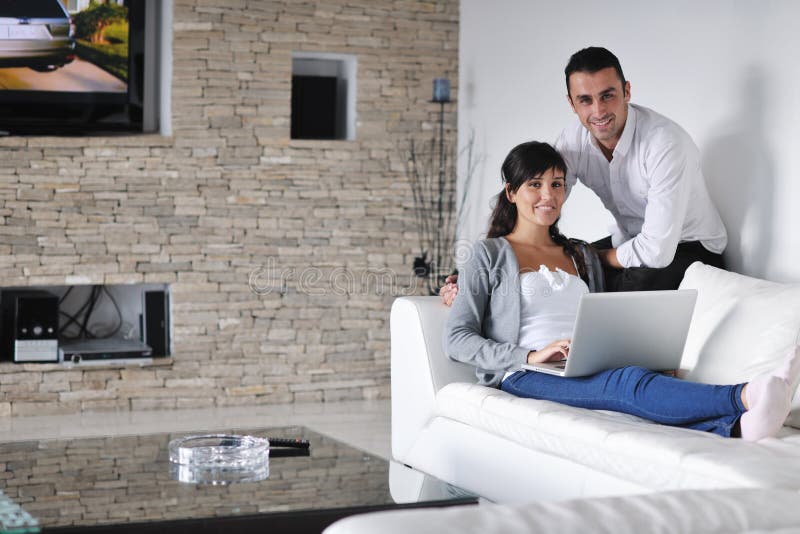 Les couples joyeux détendent et travaillent sur l'ordinateur portatif à la maison photos libres de droits Les couples joyeux détendent et travaillent sur l'ordinateur portatif à la maison photos libres de droits