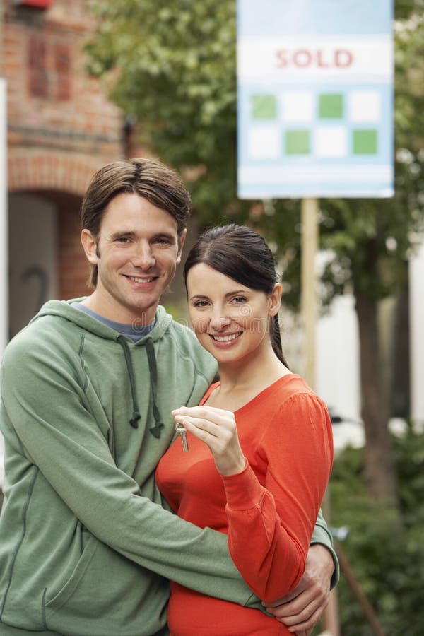 Les couples jugeant Front Of New Home With ont vendu le signe photo libre de droits Les couples jugeant Front Of New Home With ont vendu le signe photo libre de droits
