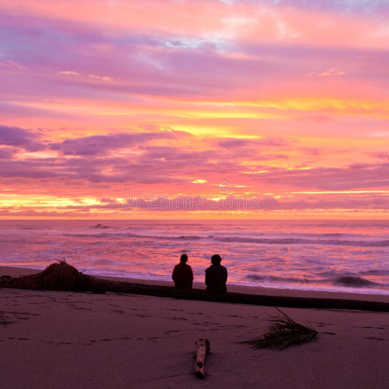 Les couples romantiques apprécient le coucher du soleil spectaculaire de plage photos libres de droits Les couples romantiques apprécient le coucher du soleil spectaculaire de plage photos libres de droits