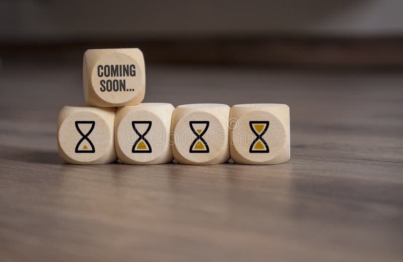 Cubes dice with hour glasses icon and coming soon on wooden background. Cubes dice with hour glasses icon and coming soon on wooden background