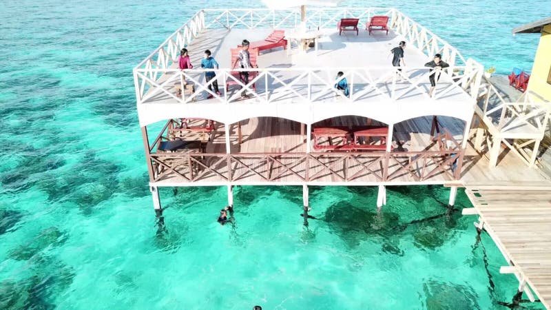 Les enfants asiatiques heureux de vue aérienne se détachent de la terrasse et du bain de complexe dans les eaux cristallines.