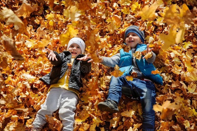 Les enfants heureux en automne garent le mensonge sur des feuilles image libre de droits Les enfants heureux en automne garent le mensonge sur des feuilles image libre de droits