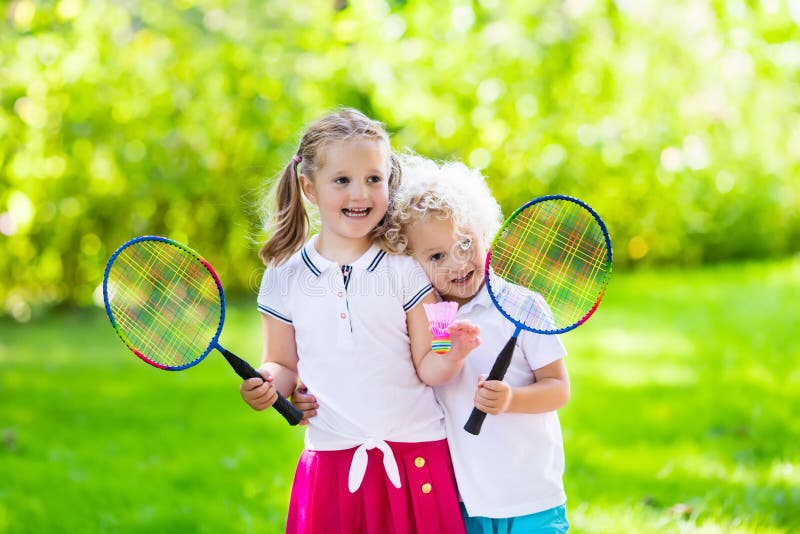 Les enfants jouent au badminton ou au tennis dans la cour extérieure image stock Les enfants jouent au badminton ou au tennis dans la cour extérieure image stock