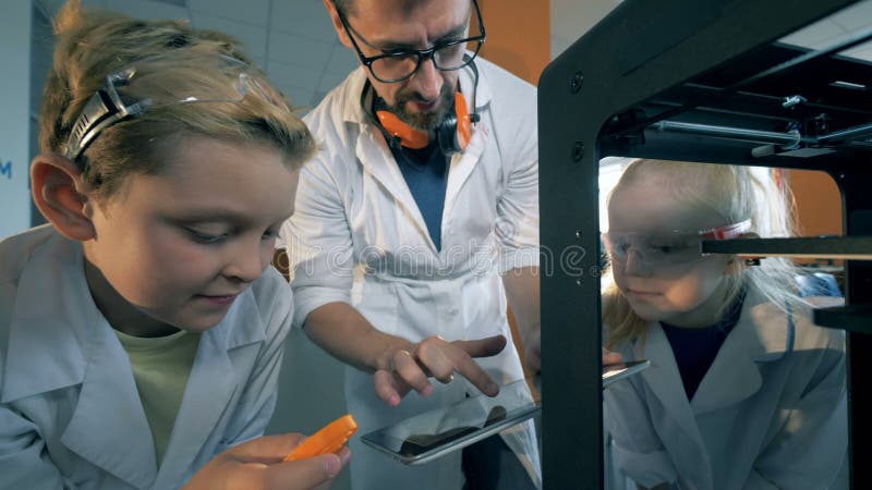 Les enfants observent de près un détail imprimé dans 3D avec un instructeur de laboratoire
