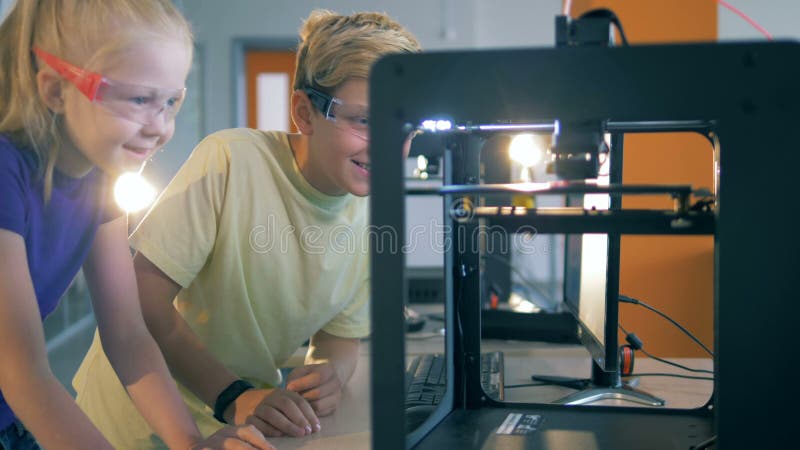 Les enfants observent un processus de l'impression 3D