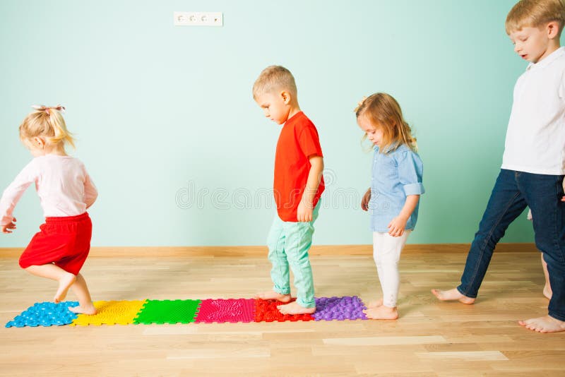 Les enfants se tiennent nu-pieds dans une rangée entre les tapis de massage photos libres de droits Les enfants se tiennent nu-pieds dans une rangée entre les tapis de massage photos libres de droits