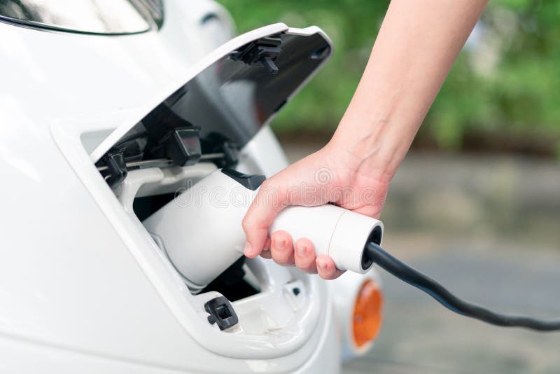 Les femmes asiatiques apportent des chargeurs de batterie se relient à la voiture électrique à images libres de droits Les femmes asiatiques apportent des chargeurs de batterie se relient à la voiture électrique à images libres de droits