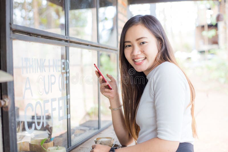 Les femmes asiatiques d'affaires textotant au téléphone intelligent dans le coffe moderne font des emplettes photographie stock Les femmes asiatiques d'affaires textotant au téléphone intelligent dans le coffe moderne font des emplettes photographie stock