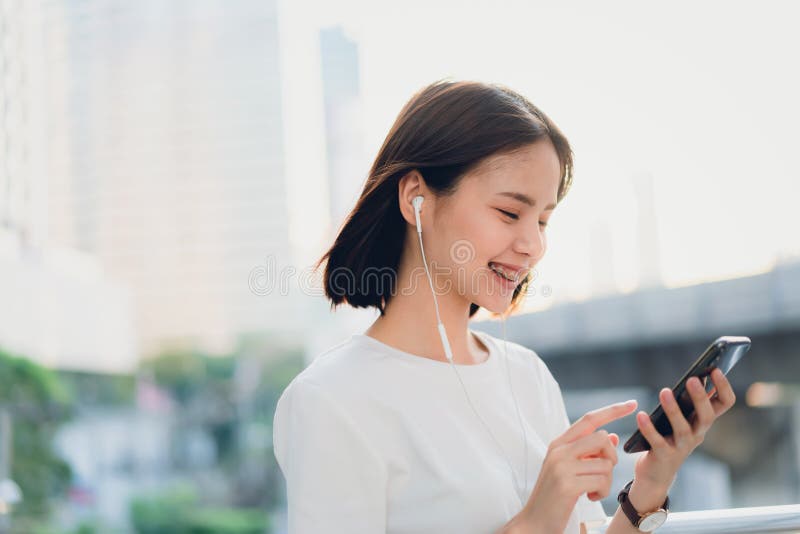 Les femmes ?coutent la musique des ?couteurs blancs Et employant le contact de mains pour employer de diverses fonctions, humeur image libre de droits Les femmes ?coutent la musique des ?couteurs blancs Et employant le contact de mains pour employer de diverses fonctions, humeur image libre de droits