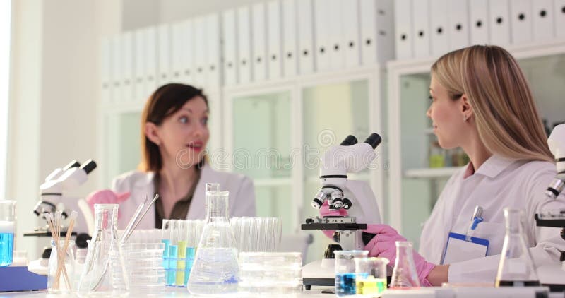 Les femmes scientifiques voient la réaction au microscope et donnent cinq