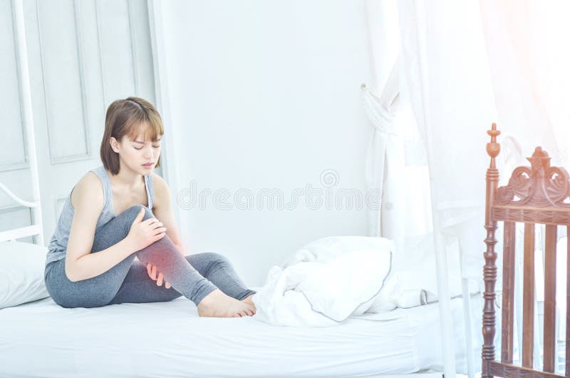 Les femmes utilisant les pyjamas gris se reposant sur le divan utilisent la poignée au pied photographie stock libre de droits Les femmes utilisant les pyjamas gris se reposant sur le divan utilisent la poignée au pied photographie stock libre de droits