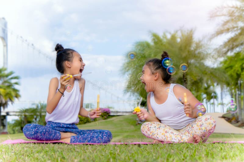 Les filles badinent la bulle de savon drôle de bonheur en parc, riant les WI heureux images stock Les filles badinent la bulle de savon drôle de bonheur en parc, riant les WI heureux images stock