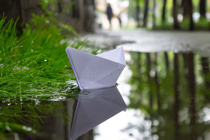 Les flotteurs de papier de bateau sur le courant après une forte pluie entre les rues de la ville image libre de droits Les flotteurs de papier de bateau sur le courant après une forte pluie entre les rues de la ville image libre de droits