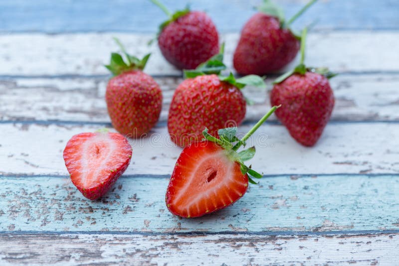 Les fraises sur la table de vintage avec une ont coupé dans la moitié image libre de droits Les fraises sur la table de vintage avec une ont coupé dans la moitié image libre de droits