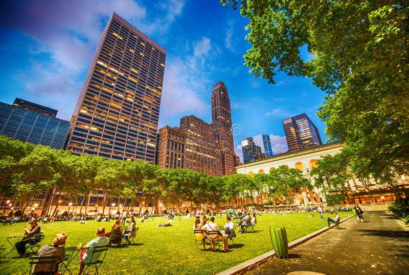 Les gens détendant sur l'herbe de Bryant Park sur un bel eveni photographie stock libre de droits Les gens détendant sur l'herbe de Bryant Park sur un bel eveni photographie stock libre de droits