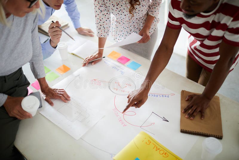 Business people standing around meeting table and analyzing business plan together at the table. Business people standing around meeting table and analyzing business plan together at the table