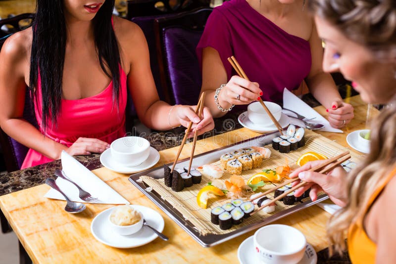 Les gens mangeant des sushi dans le restaurant asiatique photographie stock Les gens mangeant des sushi dans le restaurant asiatique photographie stock