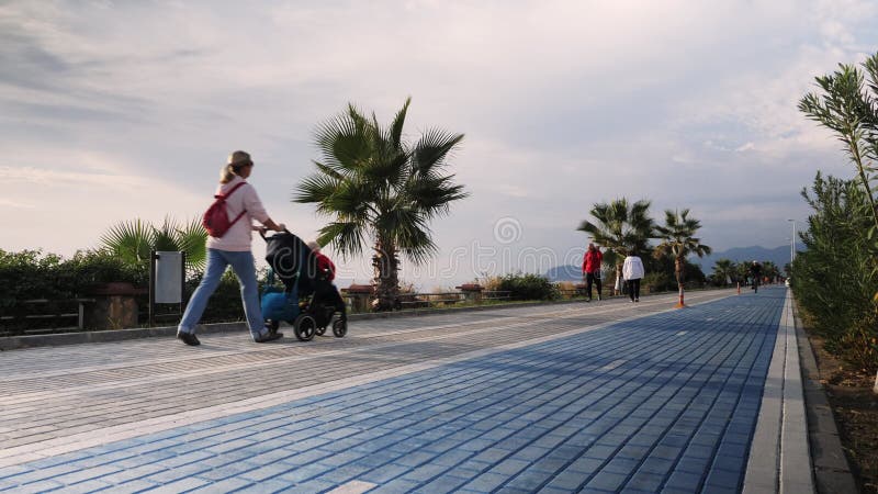Les gens marchent sur le quai de bord de mer aux jours ensoleillés. quai avec trottoir et voie cyclable. les touristes marchent su