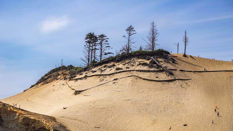 Les gens montant la dune de sable énorme au secteur d'état naturel de Kiwanda de cap, ville Pacifique un jour ensoleillé, OU, les images stock Les gens montant la dune de sable énorme au secteur d'état naturel de Kiwanda de cap, ville Pacifique un jour ensoleillé, OU, les images stock