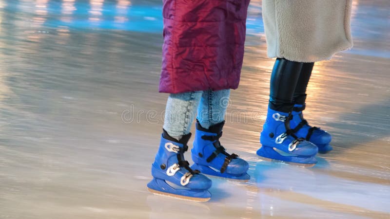 Les gens montent sur une patinoire. jambes en patins à glace. spots lumineux sur la glace 4k résolution vidéo. clips vidéos